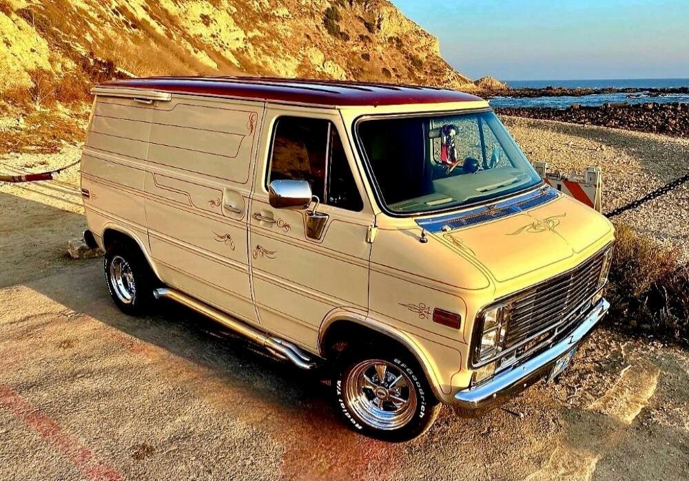 Vintage cream-colored van parked near a rocky coastline.