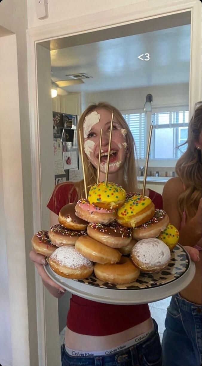 <3
Girl with frosting on her face holding a plate of donuts stacked on skewers.