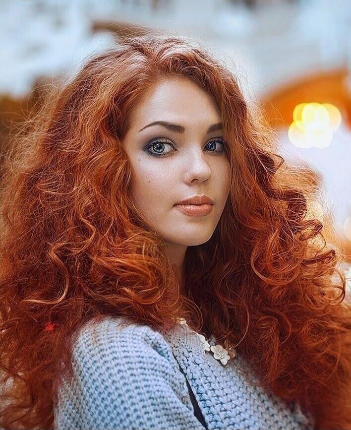 A portrait of a woman with red curly hair.