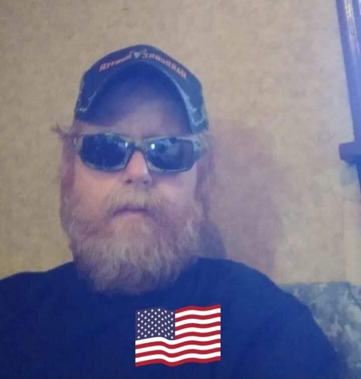 A man wearing sunglasses, a cap with 'WYOMING' text, and a t-shirt with an American flag graphic.