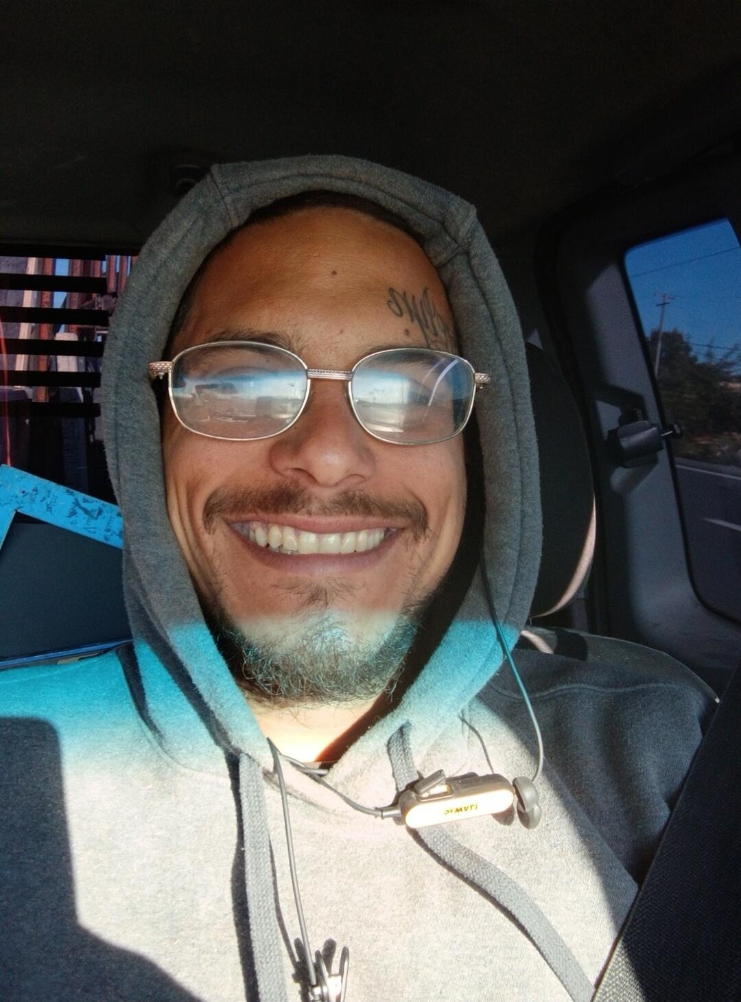 A stylized tattoo is visible on the man's forehead, but the text is not clearly legible.