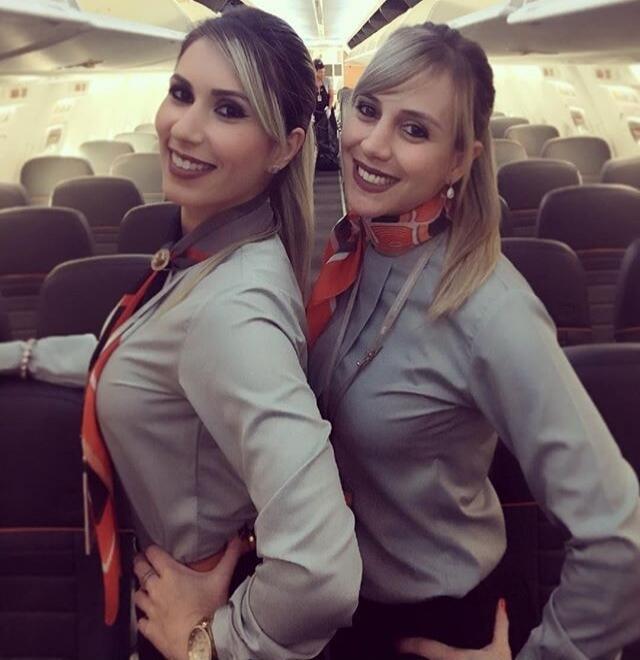 Two flight attendants posing for a photo inside an airplane.