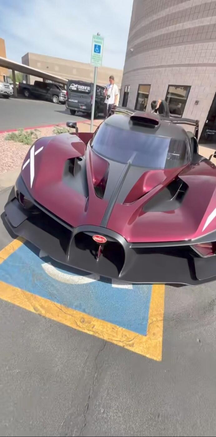 Reserved Parking. Touch N' Go Retail Co. Bugatti. A stunning Bugatti Bolide hypercar is parked in a lot, showcasing its unique design and maroon color with white 'X' markings.