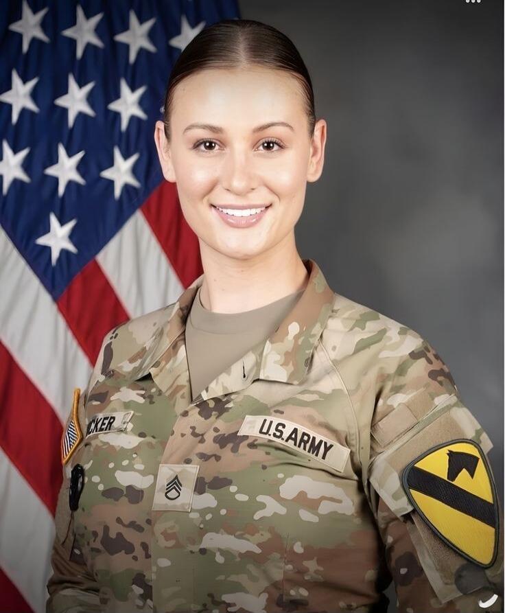 A woman in a U.S. Army uniform is smiling in front of an American flag. Her uniform shows 'U.S. ARMY' and a Staff Sergeant rank insignia. A patch for the 1st Cavalry Division is visible on her sleeve.