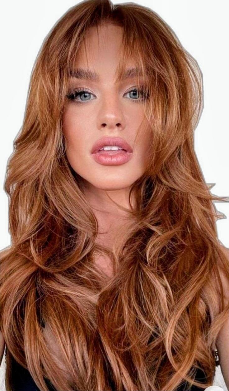 Portrait of a woman with long wavy red hair, blue eyes, and full lips.