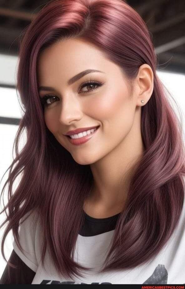 Portrait of a woman with long burgundy hair, smiling.