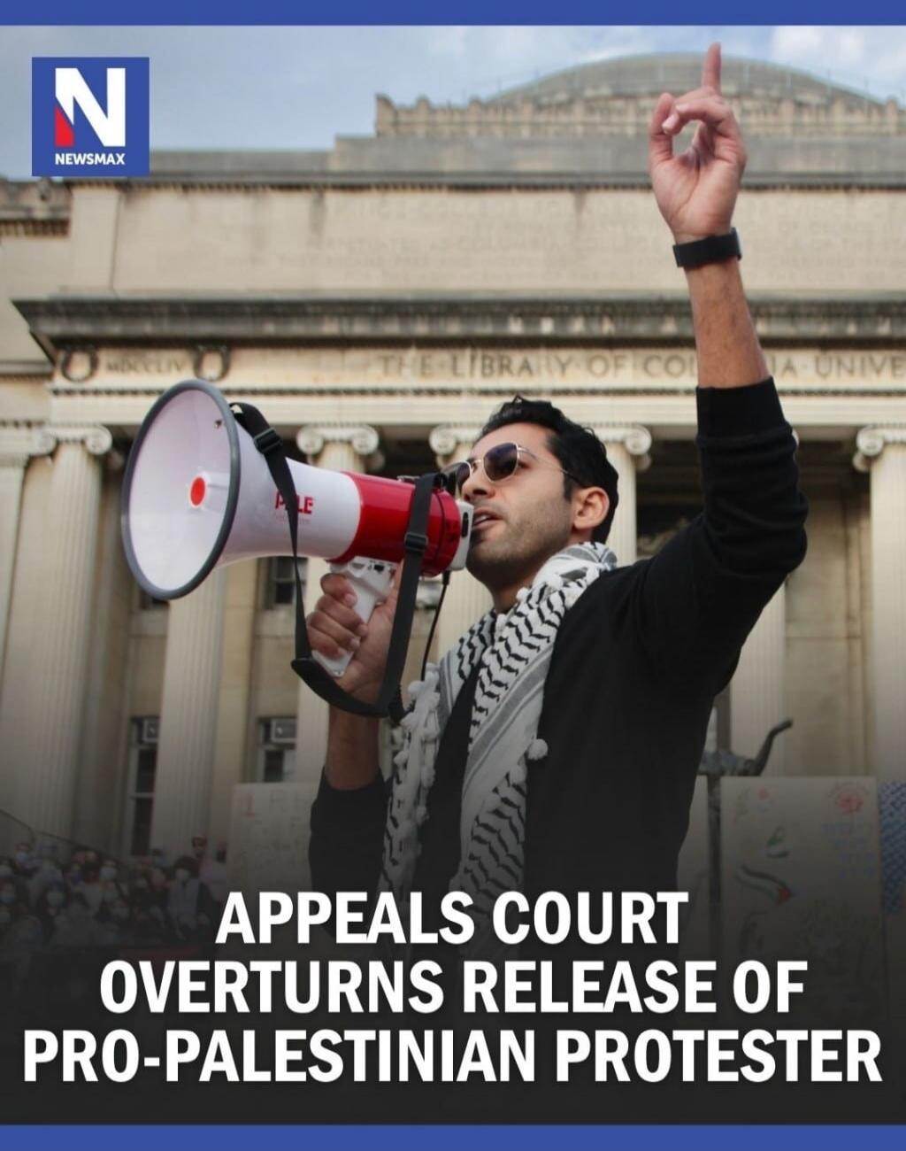 NEWSMAX. APPEALS COURT OVERTURNS RELEASE OF PRO-PALESTINIAN PROTESTER. A man is speaking into a megaphone during a protest in front of a building, possibly a library or university.