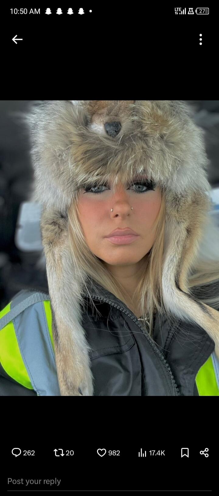 A woman wearing a furry winter hat and a high-visibility jacket.