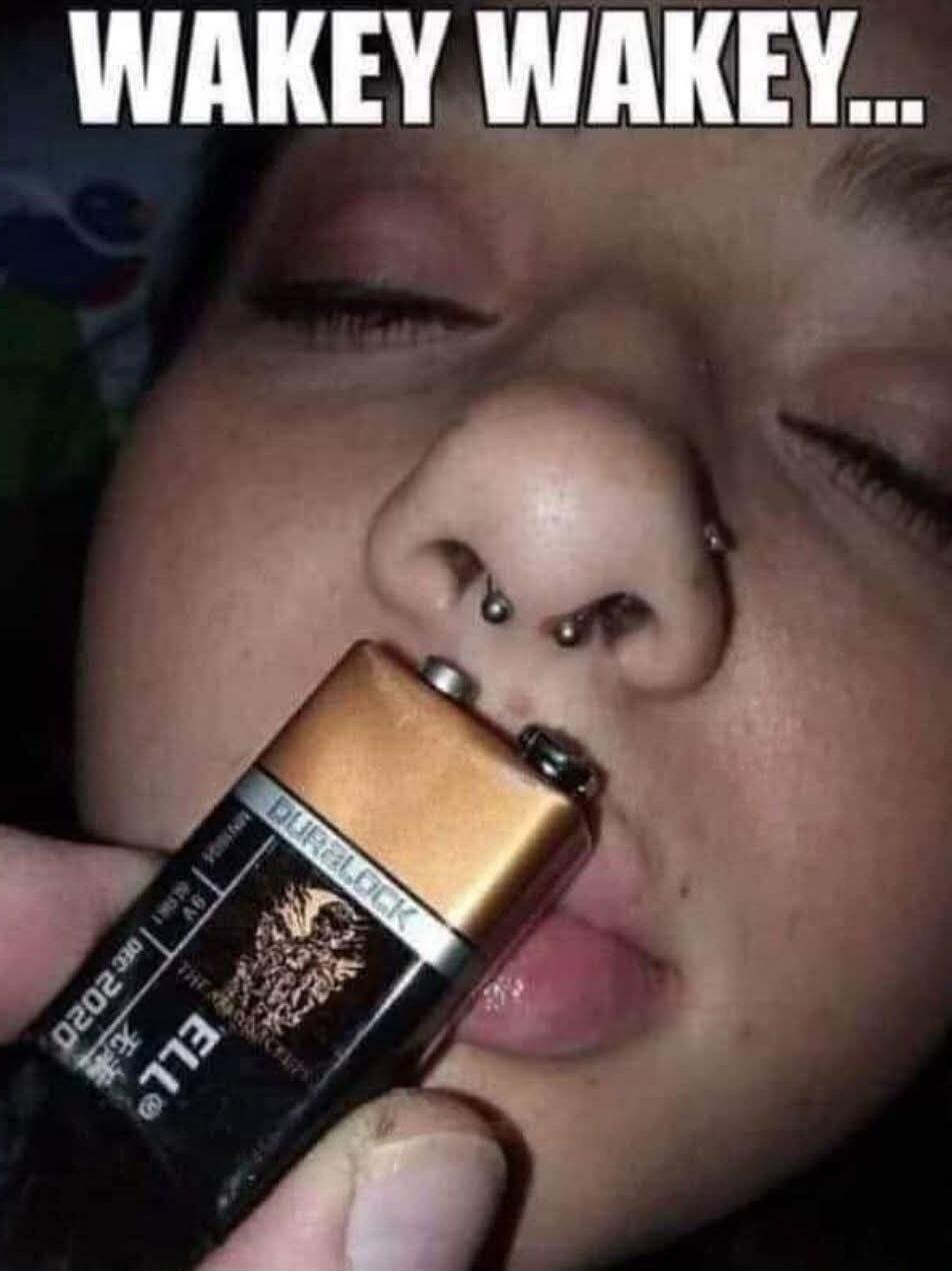 WAKEY WAKEY... A person is sleeping, and someone is holding a 9V battery to their nose, presumably to wake them up.