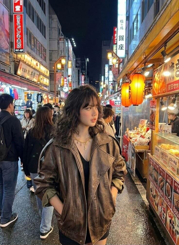 A young woman stands on a bustling street at night, illuminated by numerous signs and lanterns. Food stalls line the right side of the street, displaying prices such as 780 yen, 660 yen, 110 yen. Some signs read 'Yakishoba Pan-ya', 'Ginza', and 'Shio no ba'.