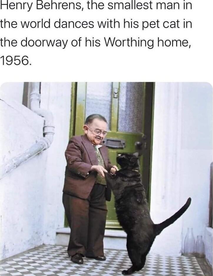 Henry Benrens the smallest man in the world dances with his pet cat in the doorway of his Worthing home 1956
