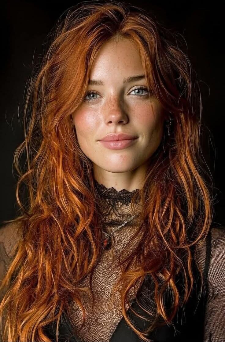 Portrait of a woman with red hair wearing a lace top.