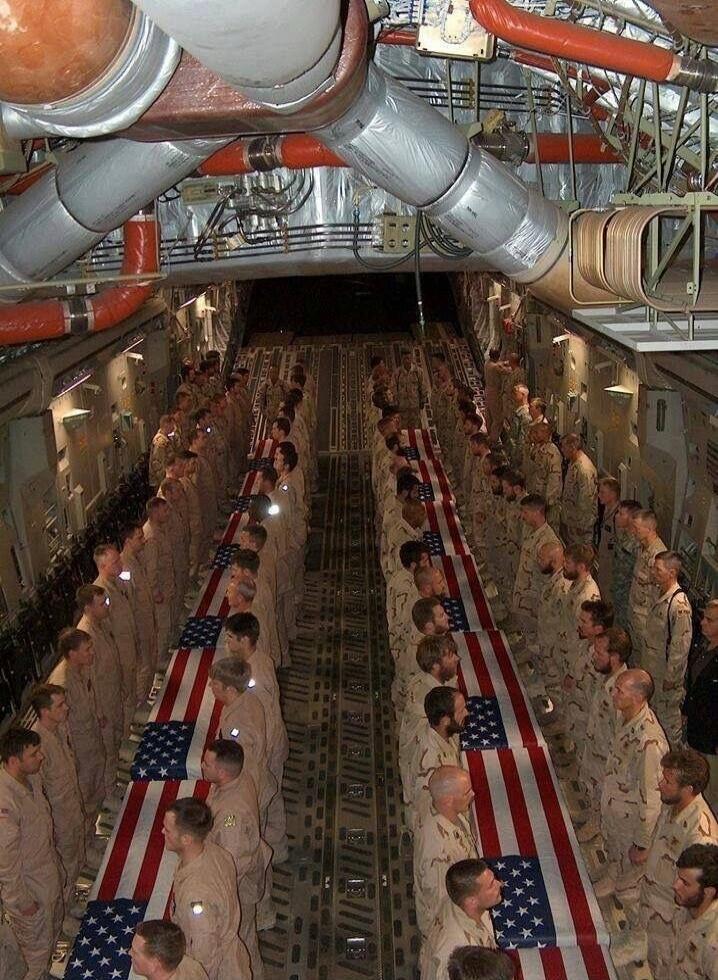 Military personnel in uniform stand solemnly inside a cargo plane, flanking several flag-draped coffins. The scene depicts a dignified transfer or repatriation ceremony for fallen soldiers.