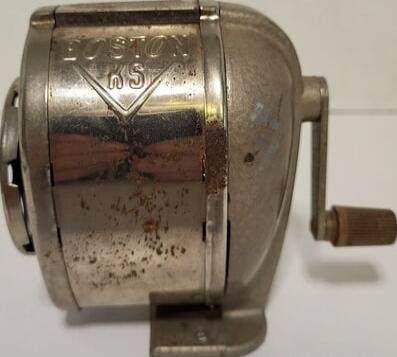 No readable text detected due to image quality. A vintage metal fishing reel with a crank handle.
