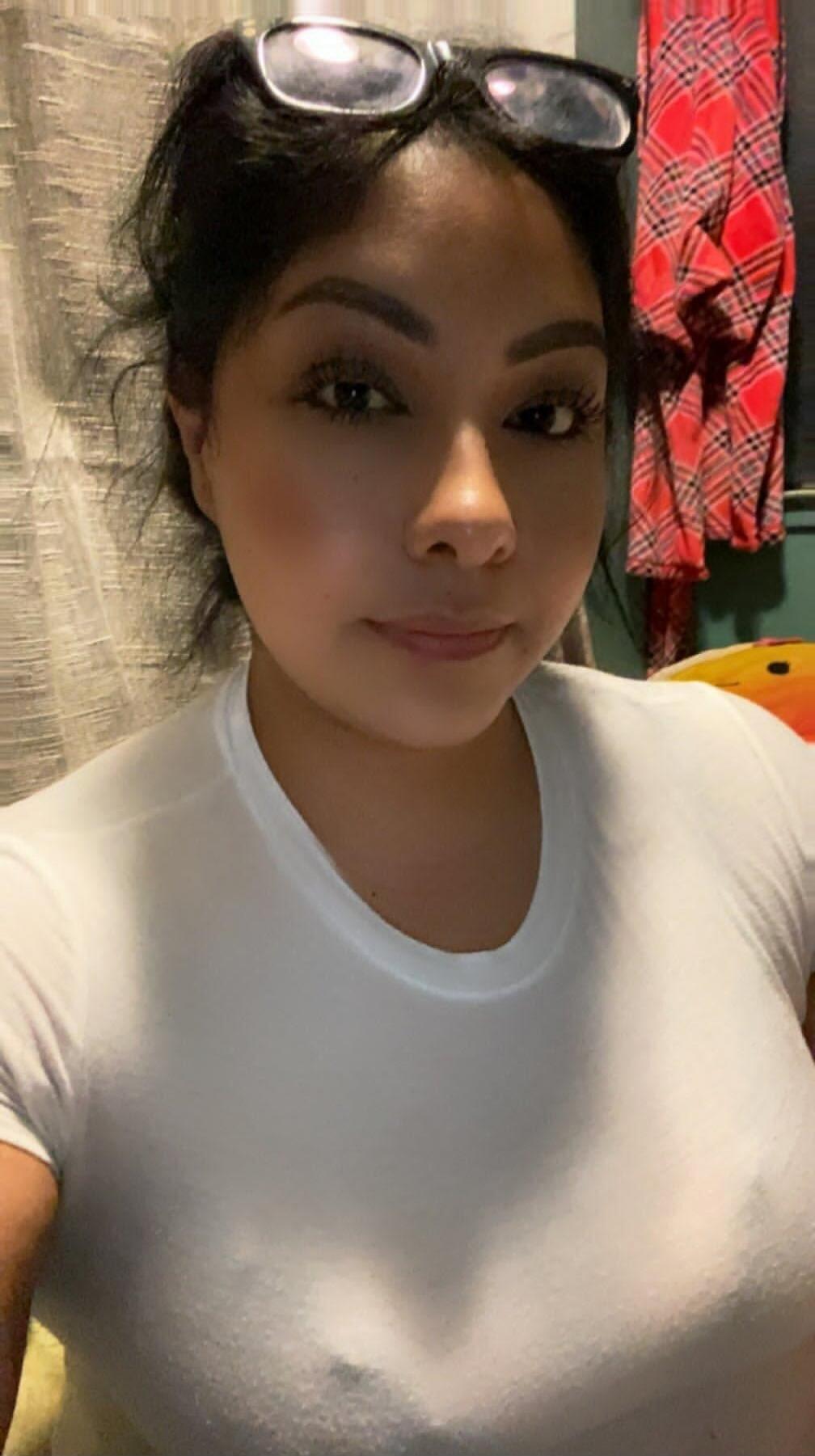 Portrait of a woman wearing a light-colored top with sunglasses resting on her head.