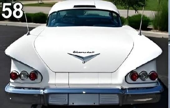 58 Chevrolet. A white 1958 Chevrolet classic car, seen from the rear, featuring prominent tail fins and triple taillights. The 'Chevrolet' emblem is visible on the trunk lid.