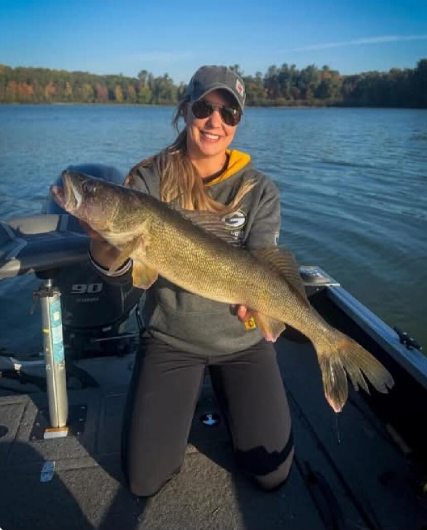 A person on a boat holding a large fish and smiling.