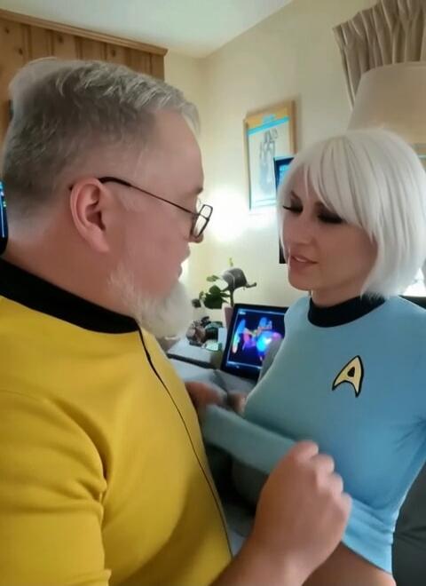 A man and a woman in Star Trek uniforms are looking at each other. The man has his hand on the woman's chest.