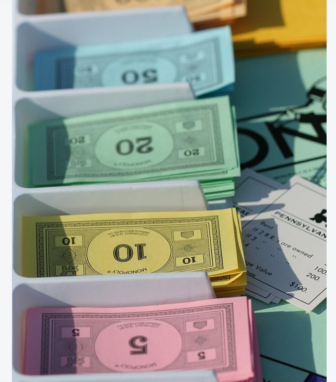 Monopoly game money and property cards. Denominations 50, 20, 10, 5. Text includes 'MONOPOLY', 'COPYRIGHT 1935 BY PARKER BROTHERS INC.', 'PENNSYLVANIA', 'Rent', 'If 2 R.R. are owned', 'ge Value', '$100'.