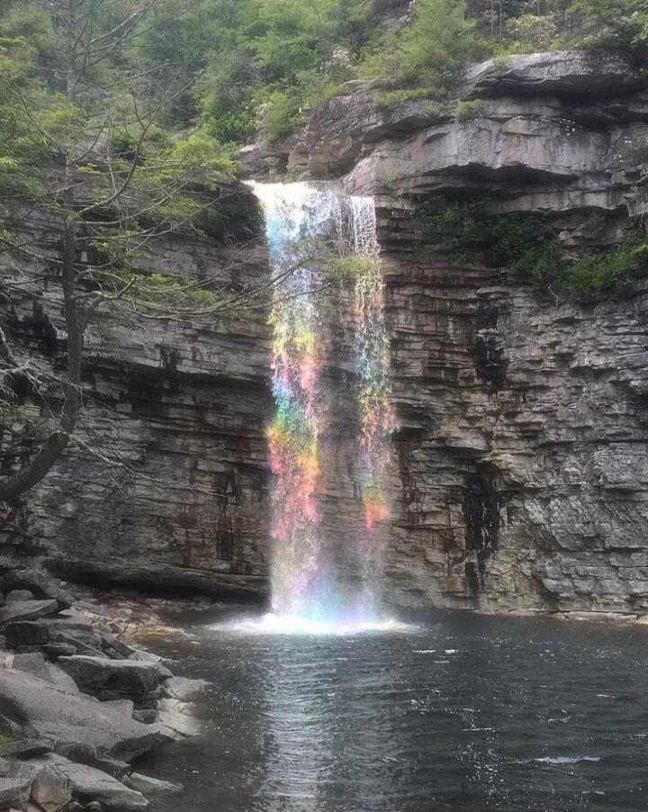 Waterfall in a rocky canyon with a rainbow-colored rainbow mist on the waterfall.