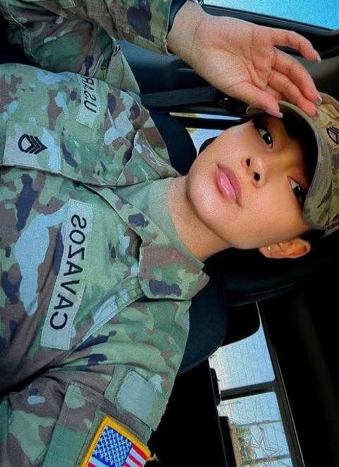 A person in a military uniform with patches, including 'SAVAS' and a rank insignia, and an American flag.