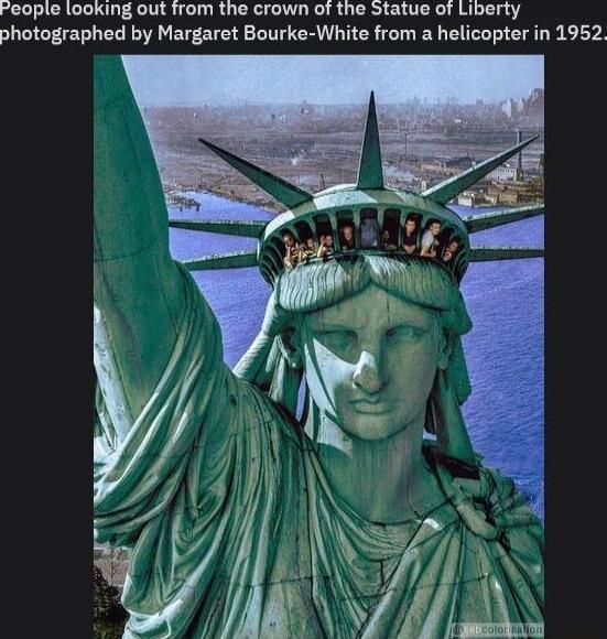 Feople looking out from the crown of the Statue of Liberty photographed by Margaret Bourke White from a helicopter in 1952