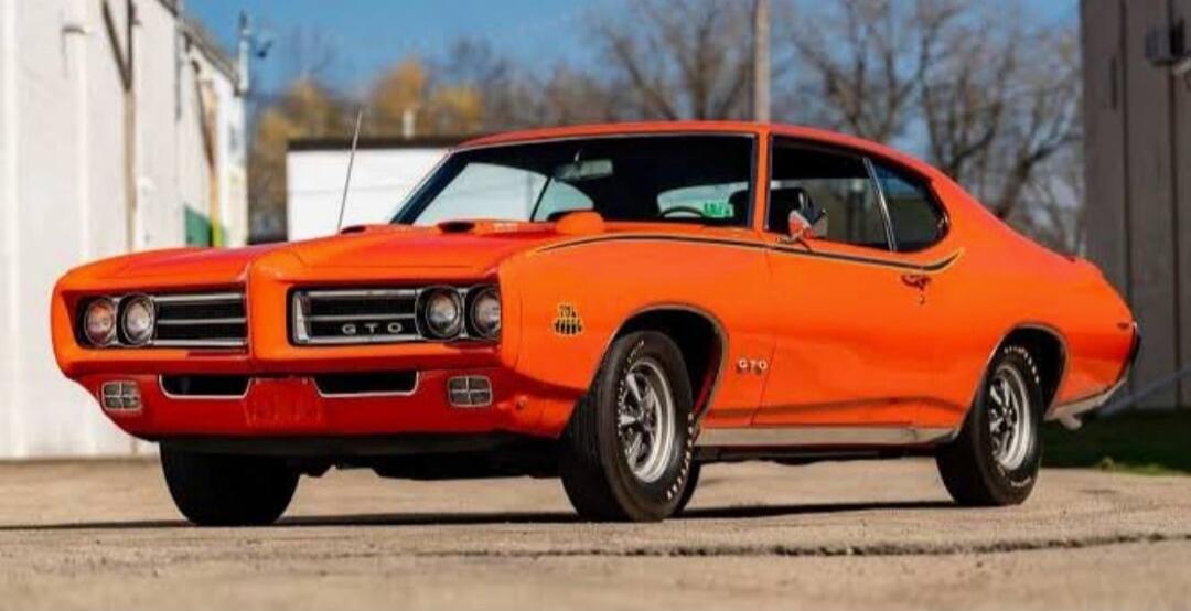 Orange classic Pontiac GTO muscle car parked on a street.