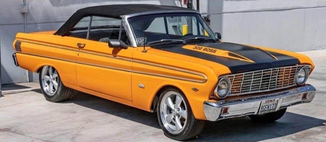 A classic orange and black convertible car, possibly a Ford Falcon, with '302 BOSS' written on its hood. The car features custom wheels and a sleek design.