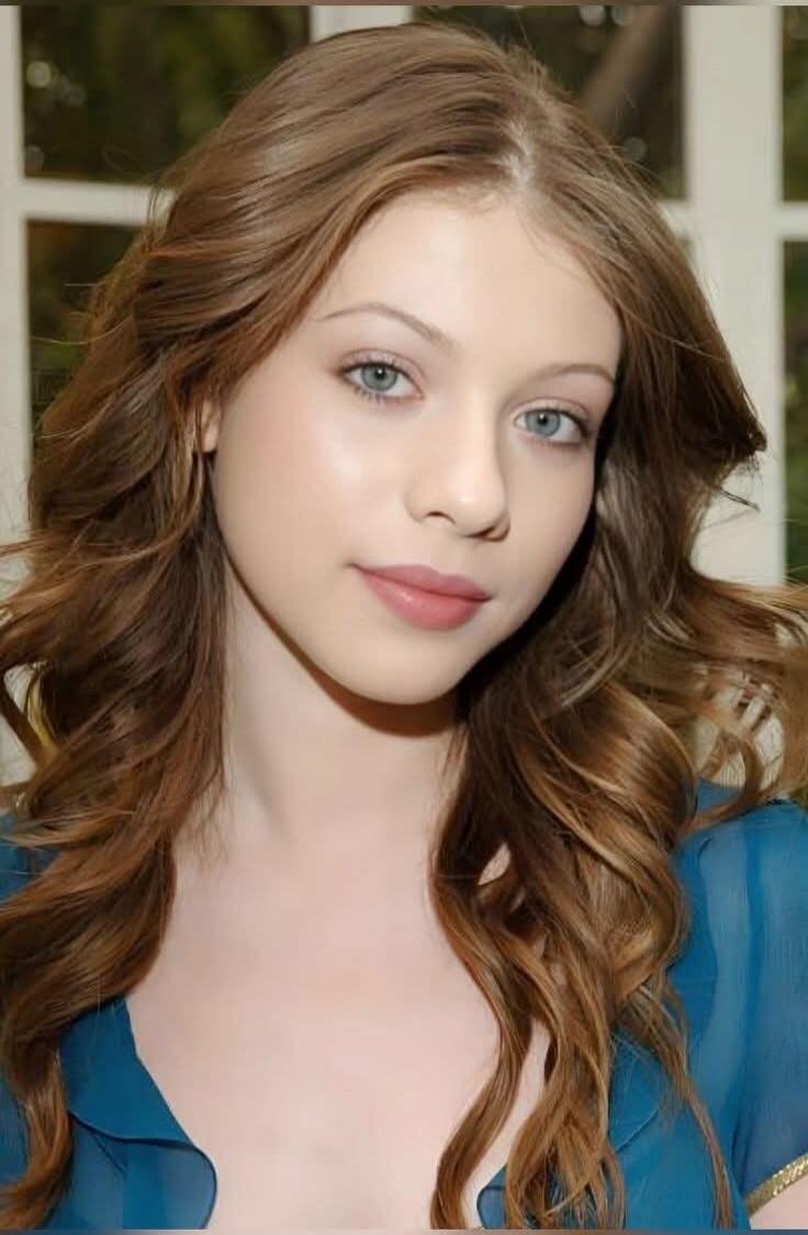 Portrait of a young woman with wavy brown hair wearing a blue top.