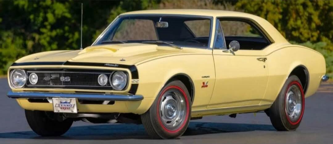 A yellow classic muscle car from the 1960s, likely a Chevrolet Camaro