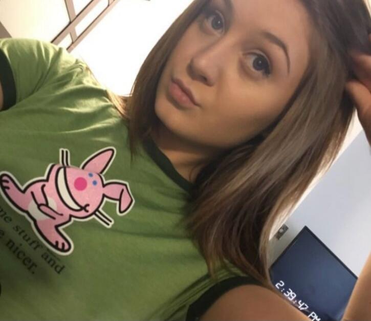 A selfie of a young woman wearing a green shirt with a pink cartoon pig.