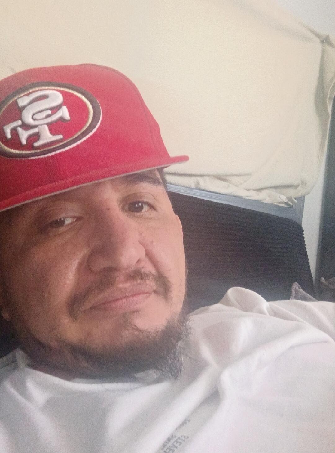 A man wearing a red baseball cap with the San Francisco 49ers logo.