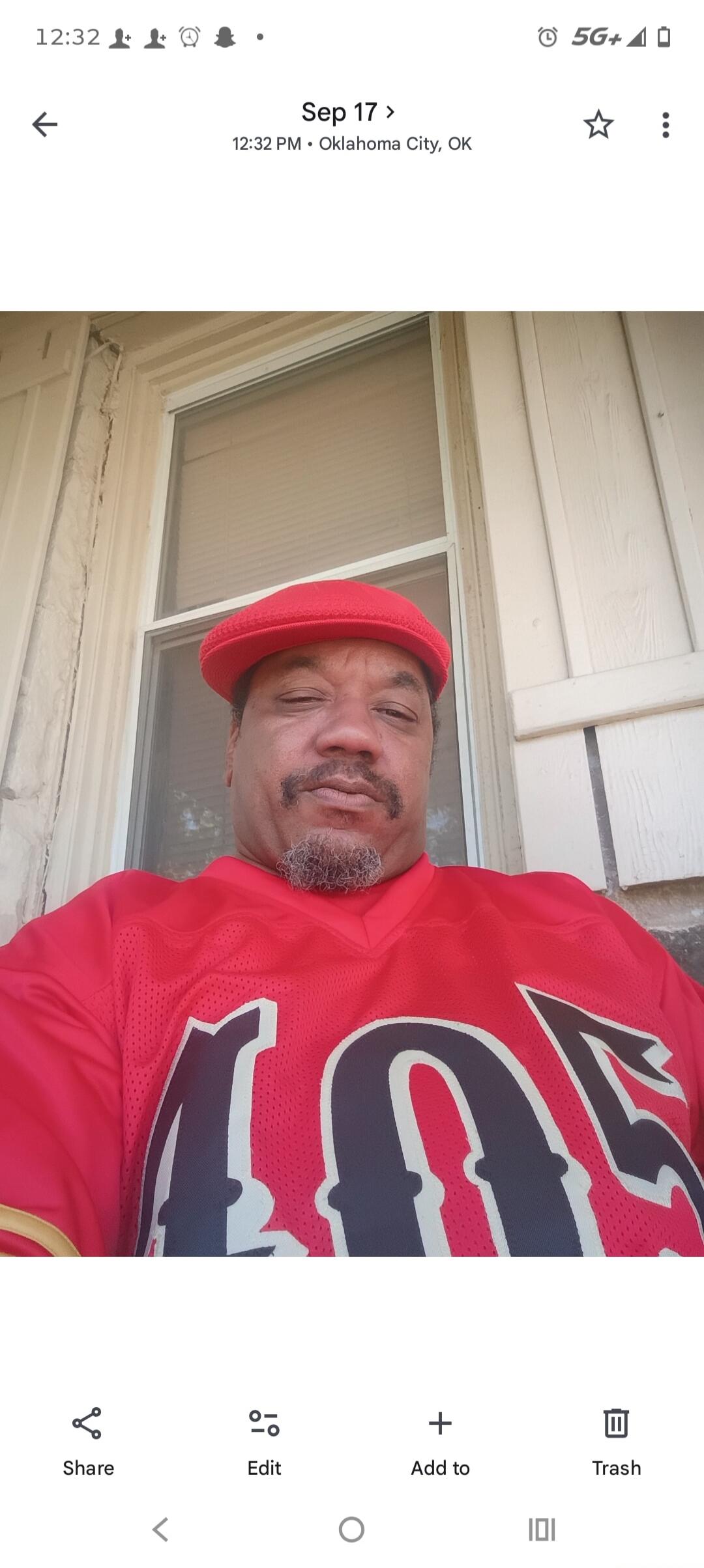 A man wearing a red hat and a red jersey with the number '405' visible, looking at the camera. The image also shows 'Sep 17', '12:32 PM • Oklahoma City, OK', 'Share', 'Edit', 'Add to', 'Trash'.