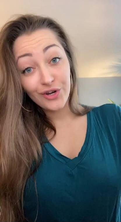 A woman is speaking directly to the camera. Her mouth is open as if mid-sentence, conveying a message or sharing thoughts.