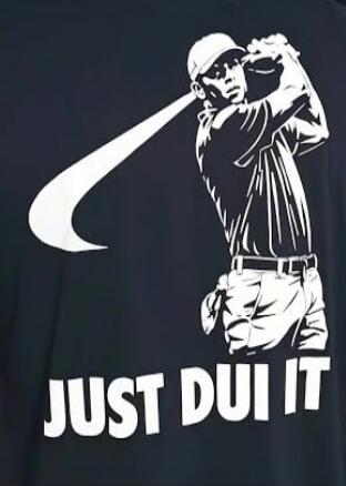 A black t-shirt with a white silhouette of a golfer, resembling Tiger Woods, in a swing pose. A large white Nike 'swoosh' logo extends from the golfer's club. Below the golfer, the text reads 'JUST DUI IT'.