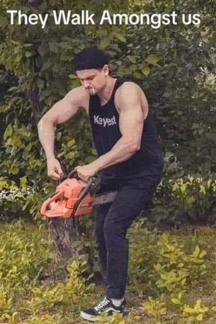 They Walk Amongst us. A muscular man is holding a running chainsaw incorrectly, with the blade pointed towards his leg, attempting to cut a tree trunk.