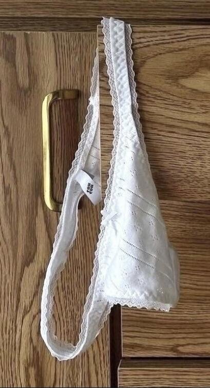 white lace bra hanging on a wooden cabinet
