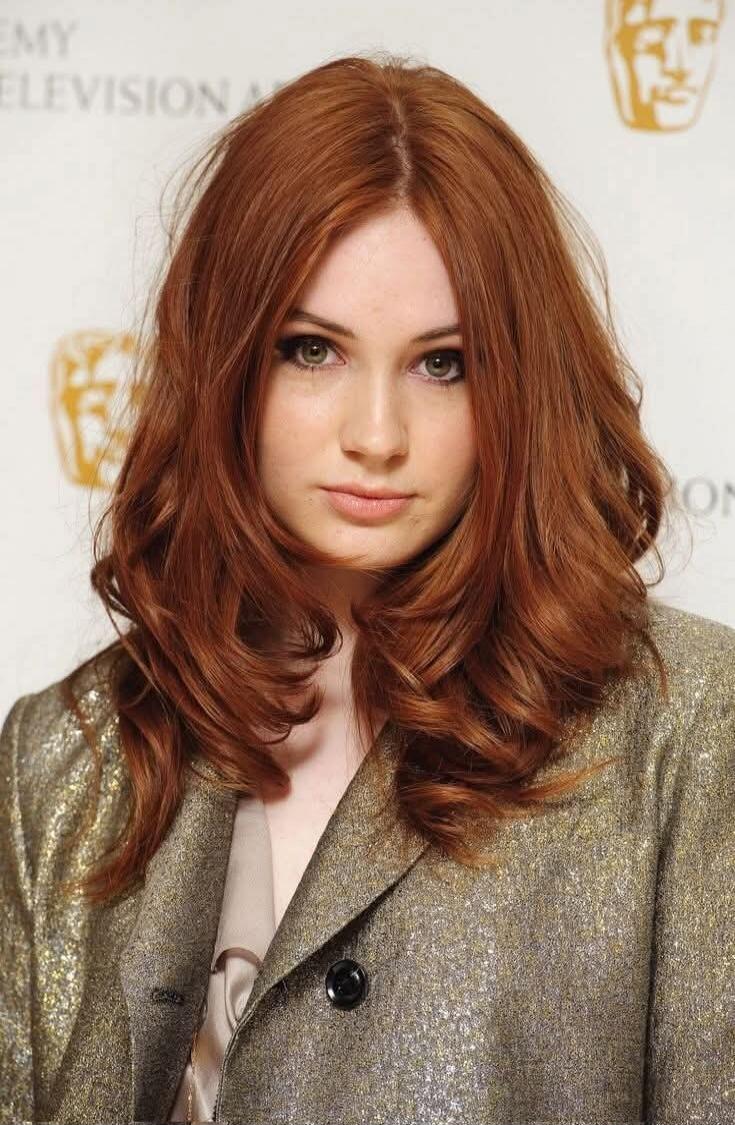 Red-haired woman in a shimmering blazer at a formal event