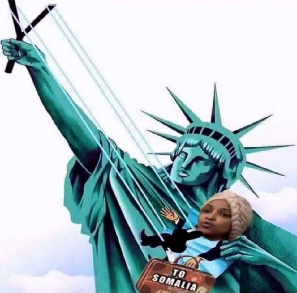 The image shows the Statue of Liberty holding strings like a puppeteer, controlling a small figure with a woman's head. The figure is holding a suitcase with the text 'TO SOMALIA'.