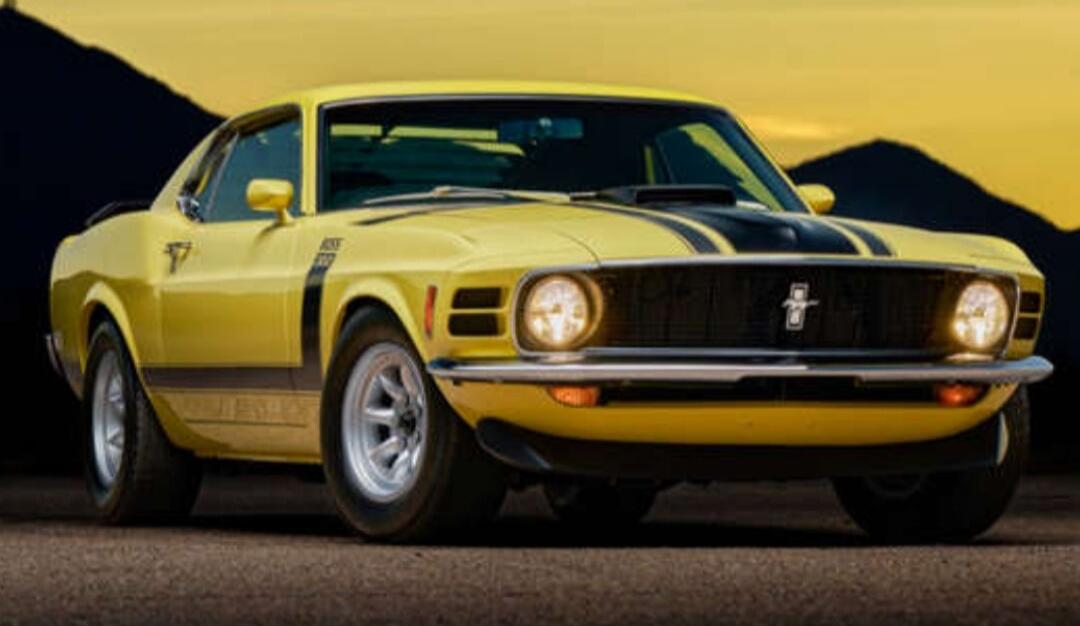 Yellow classic car with black racing stripe at sunset