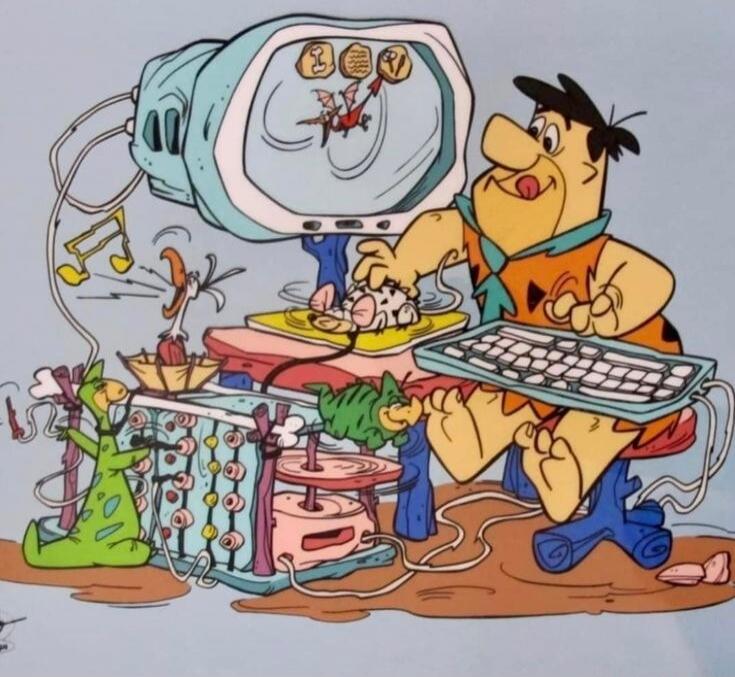 Fred Flintstone is depicted using a prehistoric computer setup. The screen shows a dragon-like character, while a real mouse on a spinning wheel acts as a computer mouse. A bird serves as a speaker, a dinosaur operates a punch card machine, and another small dinosaur provides cooling. This image humorously portrays modern technology in the Stone Ag