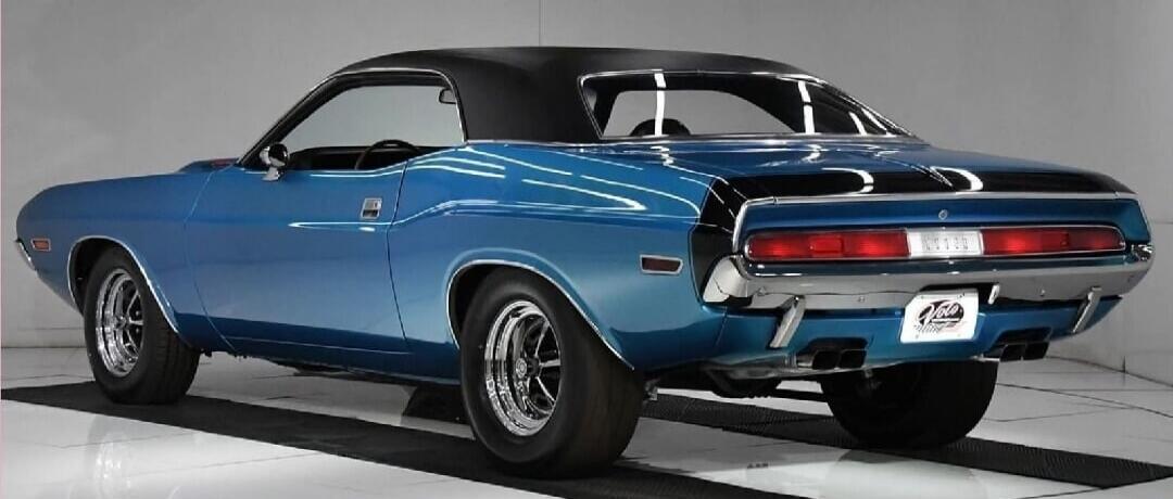 A classic blue muscle car, a Dodge Challenger, is parked in a studio setting.