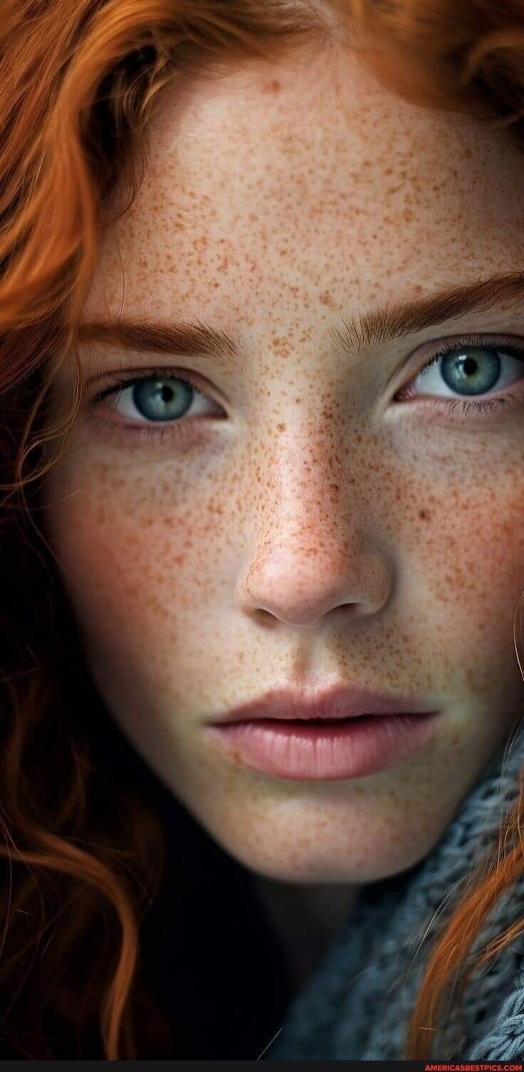 Close-up portrait of a freckled person with red hair and blue eyes.
