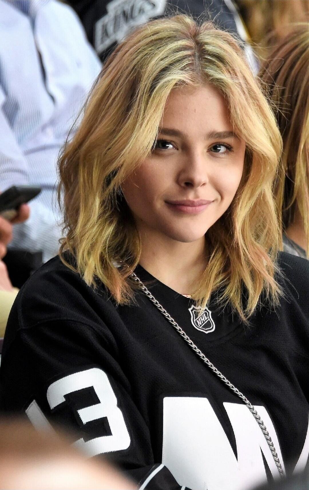 NHL logo on a black jersey; a young woman with blonde hair seated in a crowd; visible number 3 on the sleeve.
