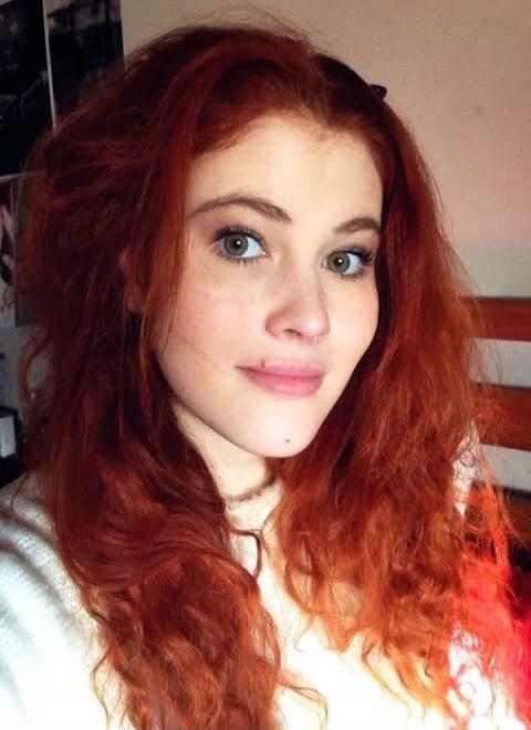 Portrait of a woman with long, wavy red hair and blue eyes.