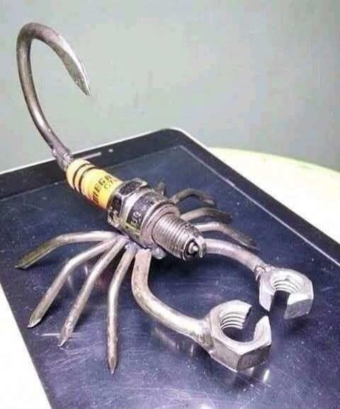 A handmade sculpture made from tools: a multi-legged creature formed from wrenches, pliers, and a spark plug.