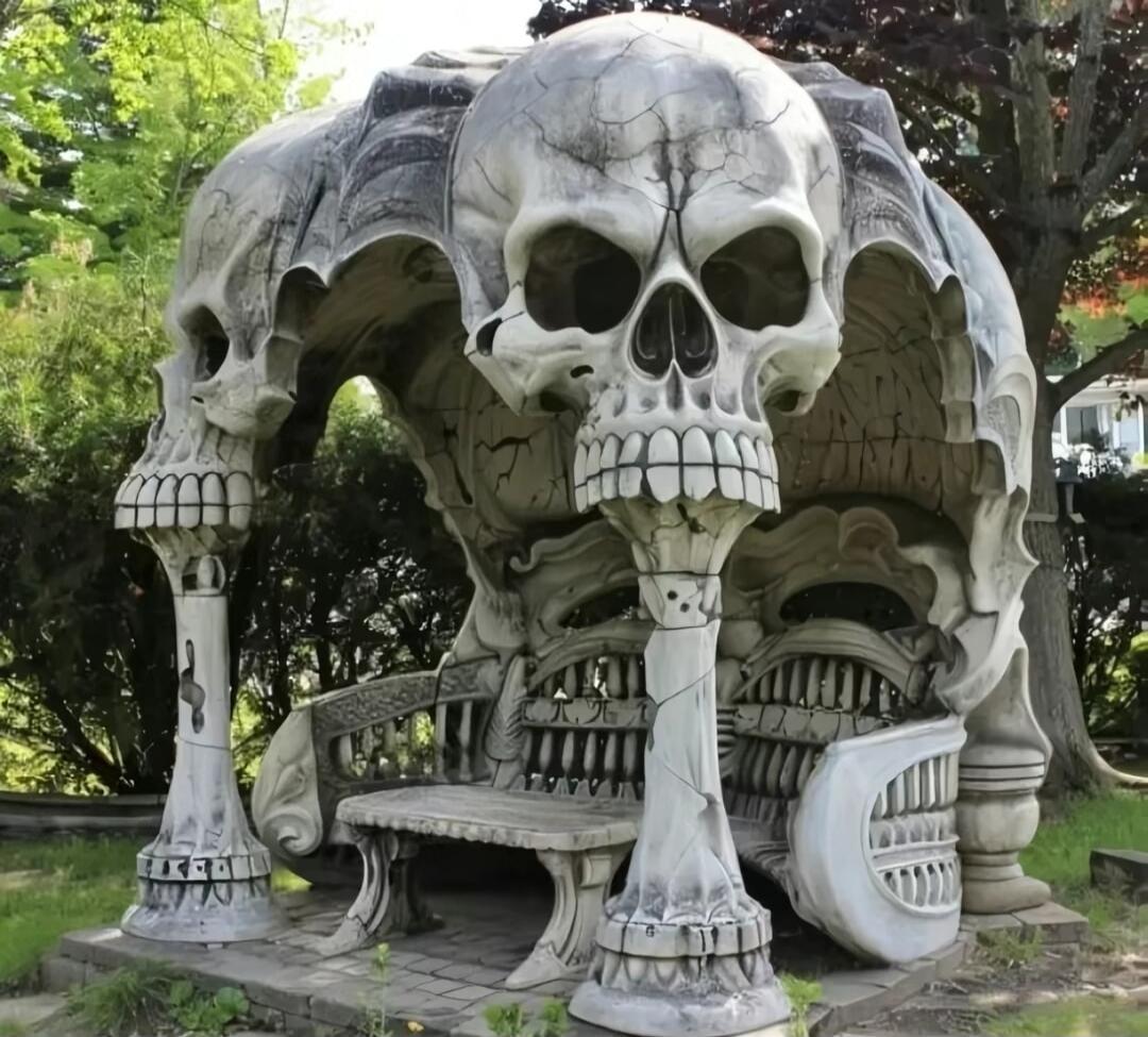 Skull-shaped outdoor sculpture resembling a gazebo with benches.