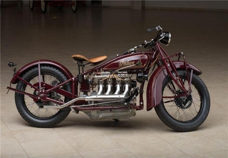 A vintage Indian 4 motorcycle, maroon color, with a brown leather seat. The text 'Indian 4' is visible on the fuel tank.