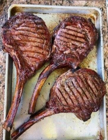 Three grilled lamb chops on a baking tray.