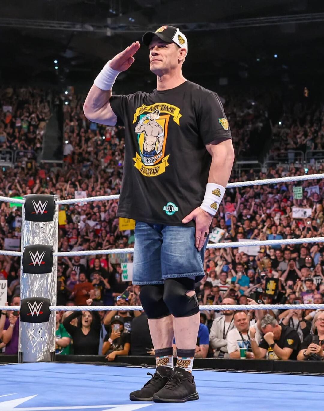 John Cena in a wrestling ring saluting the crowd.